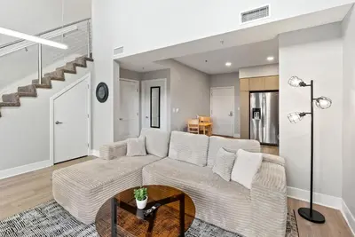 a living room with a couch and a staircase at Spacious Loft- Hollywood Free Pool, Parking, Gym in Los Angeles