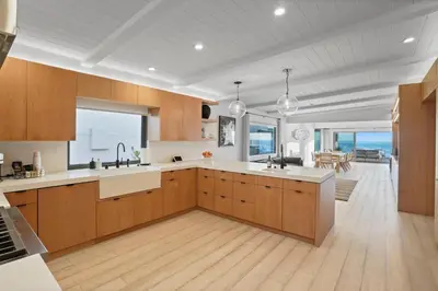 a kitchen with wooden cabinets and a view of the ocean at The Surf Lodge Villa in Malibu