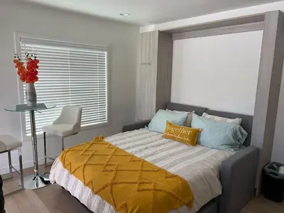 a bedroom with a bed with a yellow blanket and a window at Private guest cottage in Long Beach