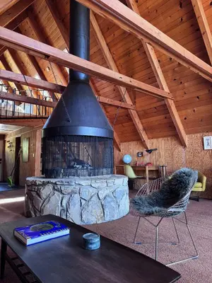 a living room with a large stone fireplace in a house at A-Frame with Carousel Fireplace in Running Springs