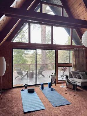 a living room with blue yoga mats in front of a large window at A-Frame with Carousel Fireplace in Running Springs