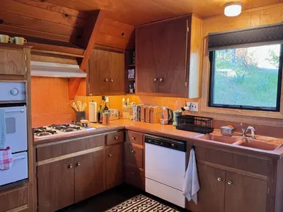 a kitchen with wooden cabinets and a stove and a sink at A-Frame with Carousel Fireplace in Running Springs