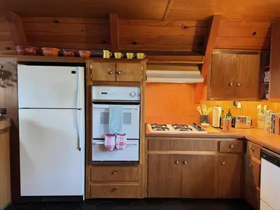 a white refrigerator in a kitchen with wooden cabinets at A-Frame with Carousel Fireplace in Running Springs