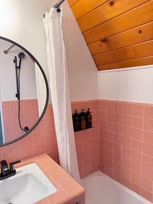 a bathroom with a sink and a shower with pink tile at A-Frame with Carousel Fireplace in Running Springs
