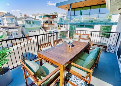 a wooden table and chairs on a balcony at Beach House Steps to the Sand! in Manhattan Beach