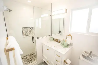 a white bathroom with a shower and a sink at Beach House Steps to the Sand! in Manhattan Beach