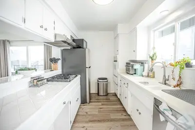 a kitchen with white cabinets and a stainless steel refrigerator at Beach House Steps to the Sand! in Manhattan Beach