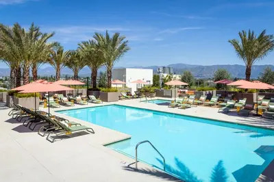 a pool with chairs and umbrellas at a hotel at Heart of North Hollywood 2 bed Apt FREE parking, hot tub, pool, gym in Garnsey