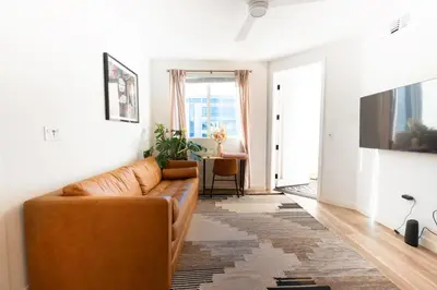 a living room with a brown couch and a table at Heart of North Hollywood 2 bed Apt FREE parking, hot tub, pool, gym in Garnsey