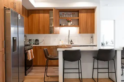 a kitchen with a counter with stools and a refrigerator at Heart of North Hollywood 2 bed Apt FREE parking, hot tub, pool, gym in Garnsey