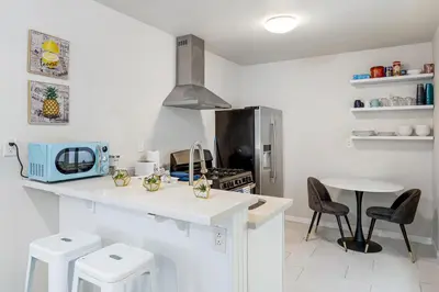 a white kitchen with a counter and a table at Comfy Home Near Sofi Stadium 2 in Los Angeles