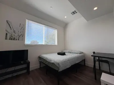a small bedroom with a bed and a television at Blue Central Stay Near USC, BMO Stadium & Downtown LA in Los Angeles