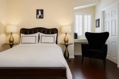 a bedroom with a bed and a black chair at The Heart Of Hollywood Hills in Los Angeles