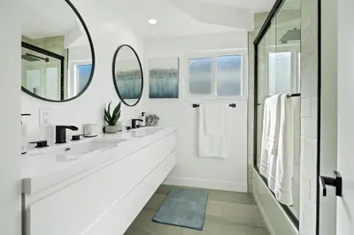 a white bathroom with two sinks and a mirror at House with pool in prime location - 10 mins to Universal Studio in Garnsey