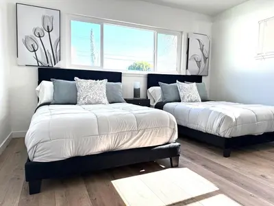 a bedroom with two beds and two windows at House with pool in prime location - 10 mins to Universal Studio in Garnsey