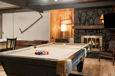 a pool table in a room with a fireplace at Timber Wolf Tavern - Walk to Slopes, Game Room, Pool Table, BBQ in Big Bear Lake