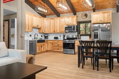 a kitchen with wooden cabinets and a table and chairs at Timber Wolf Tavern - Walk to Slopes, Game Room, Pool Table, BBQ in Big Bear Lake