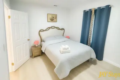 a small bedroom with a bed with blue curtains at Newly renovated, warm home with 4 bedrooms, 14 miles from Disney in Whittier