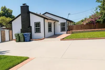 a house with two trash cans in the driveway at Newly renovated, warm home with 4 bedrooms, 14 miles from Disney in Whittier