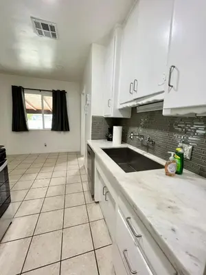 a kitchen with white cabinets and a sink at Cozy 3BR Home With Pool, Yard, Garage, and 80 inch TV! in Van Nuys