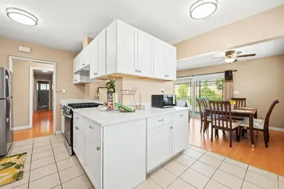 a kitchen with white cabinets and a dining room at Modern 4B Retreat with Cozy Decor in Upland
