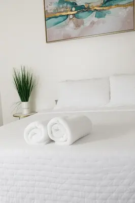 a white bed with a pile of towels on it at Ocean Breeze Marina Suites with Pool, Gym & Hot Tub in Los Angeles