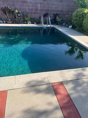 a swimming pool with blue water next to a brick wall at Pool Front Romantic Getaway withPrivate Entry in North Hills