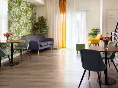 a living room with a couch and tables and chairs at Forty First Place - Boutique Hostel in Los Angeles