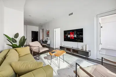 a living room with a couch and a tv on a wall at Spacious 1BDR near Walk of Fame with Luxury Amenities in Los Angeles