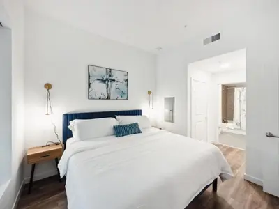 a white bedroom with a large bed with a blue headboard at Spacious 1BDR near Walk of Fame with Luxury Amenities in Los Angeles