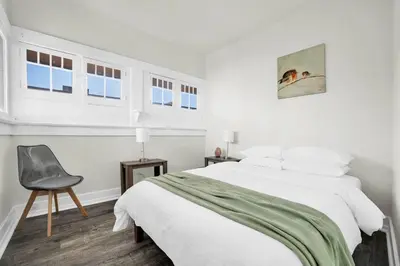 a white bedroom with a bed and a chair at Charming Craftsman Near DTLA in Los Angeles
