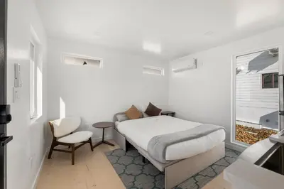 a white bedroom with a bed and a chair at Pacific Coast Suites - Oceanfront Living in Los Angeles