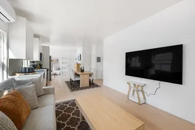 a living room with a large flat screen tv on a white wall at Pacific Coast Suites - Oceanfront Living in Los Angeles