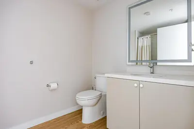 a white bathroom with a toilet and a mirror at Blueground Downtown elevator nr parks LAX-1251 in Los Angeles
