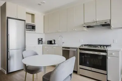 a kitchen with white cabinets and a white table and chairs at Blueground Downtown AC elevator nr parks LAX-1253 in Los Angeles
