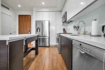 a kitchen with stainless steel appliances and wooden floors at The Sky Gem in Los Angeles