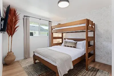 a bedroom with a wooden bunk bed with white sheets at Coastal Living and Family Friendly in Summerland
