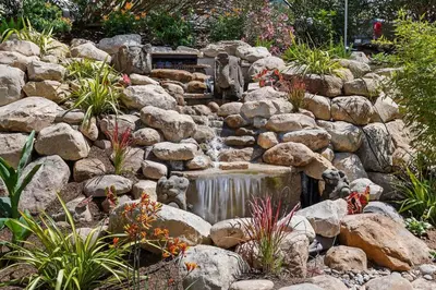 a waterfall in a garden with rocks and plants at Coastal Living and Family Friendly in Summerland
