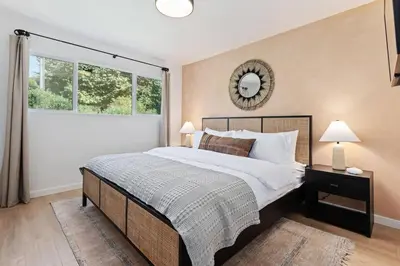 a bedroom with a bed and a mirror on the wall at Coastal Living and Family Friendly in Summerland