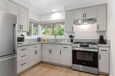 a kitchen with white cabinets and a stove top oven at Coastal Living and Family Friendly in Summerland