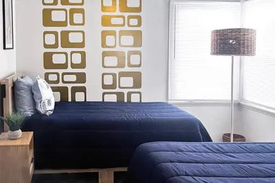 a bedroom with two beds with blue sheets and a lamp at Quaint Mid-Century Cottage by the Coast in Ventura
