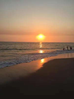 a sunset on the beach with people in the water at Quaint Mid-Century Cottage by the Coast in Ventura