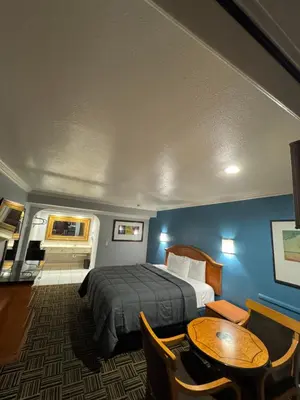 a hotel room with a bed and a table at Sunset Inn & Suites in Gardena