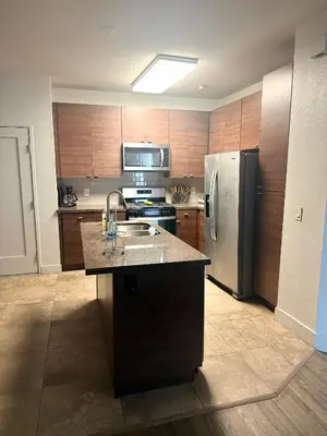 a kitchen with wooden cabinets and a stainless steel refrigerator at Villa Marina - AMAZING Modern, Spacious, Stylish 2 Master Suites in CENTRAL Marina Del Rey in Los Angeles