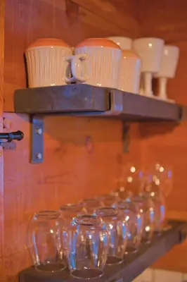a bunch of glasses sitting on a shelf with a bunch at Ray's Dear Cottage in Wrightwood