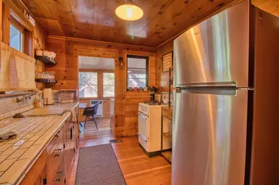 a kitchen with a stainless steel refrigerator in a cabin at Ray's Dear Cottage in Wrightwood