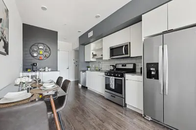 a kitchen with white cabinets and a table and a refrigerator at Hollywood 1bdr Comfort with Pool, Gym, Free Parking in Los Angeles