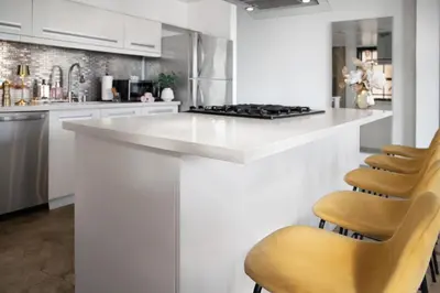 a white kitchen with a white counter and chairs at Stylish loft 2 queens & 2 sofas in Los Angeles