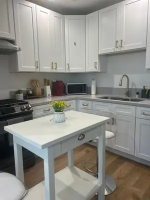 a kitchen with white cabinets and a table with flowers on it at Newly Gated Stylish Steps to Hollywood 2B2B in North Sherman Way