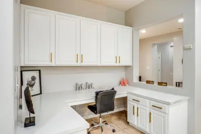a white kitchen with a desk and a chair at 8 Mi to Beach Park Bakersfield Gem with Yard! in Bakersfield